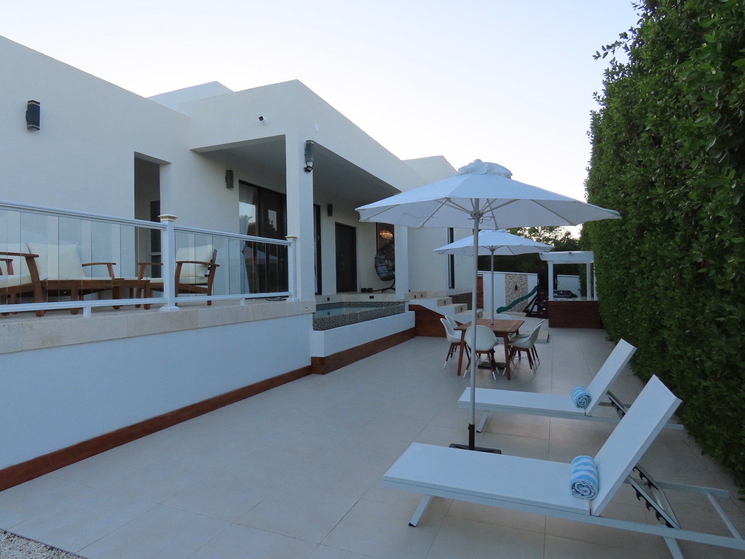 Daytime exterior of the guest house with sun loungers and patio seating