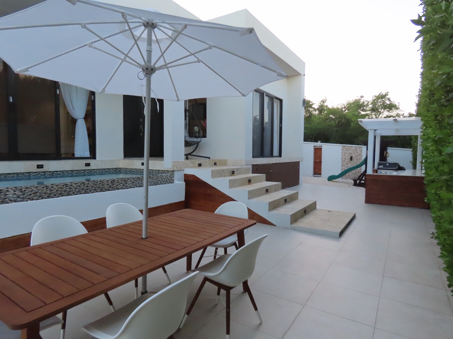 Outdoor dining table beneath umbrella beside the guest house