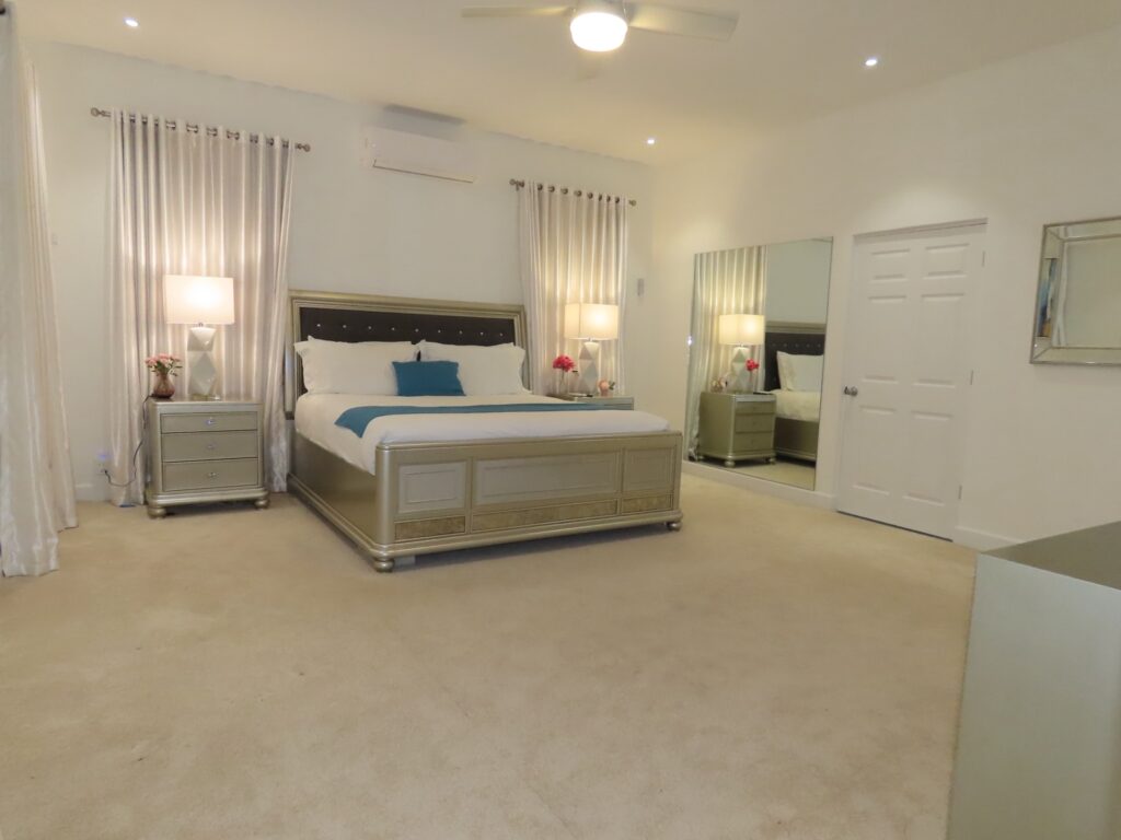 Spacious guest house bedroom with king bed, bedside lamps and curtains